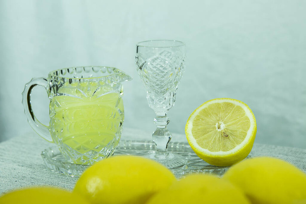 リモンチェッロ。伝統的な自家製レモンリキュールのリモンチェッロと新鮮な柑橘類を白いプレートに、選択的なフォーカス. - 写真・画像