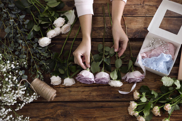Florist making beautiful wedding bouquet at wooden table, top view - Fotó, kép