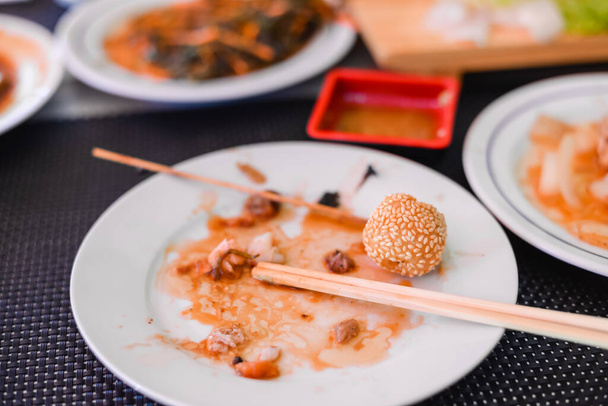 left over food on wooden table with chopsticks in chinese restaurant - Photo, image