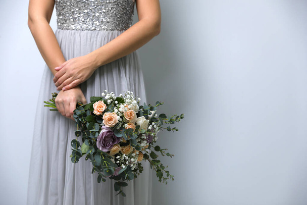 Bride holding beautiful wedding bouquet on light grey background, closeup. Space for text - Foto, imagen
