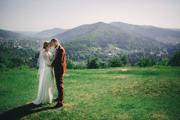 boldog elegáns menyasszony és vőlegény fut, és szórakozás a hegyekben a nyári napsütéses napon. gyönyörű friss házasok nevetnek, igaz érzelmek. érzelmi romantikus pillanat - Fotó, kép