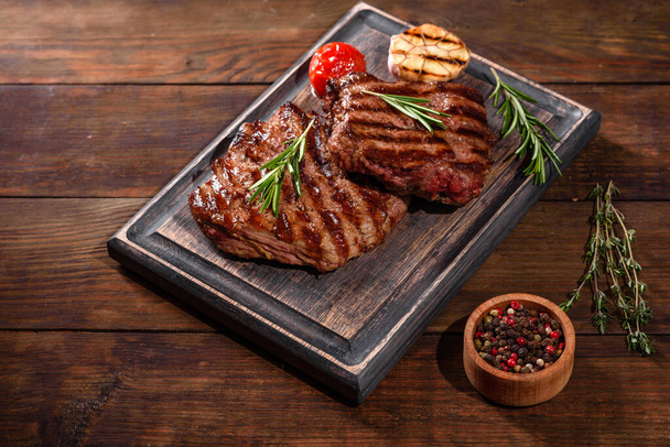 Fresh juicy delicious beef steak on a dark background. Meat dish with spices and herbs - Φωτογραφία, εικόνα