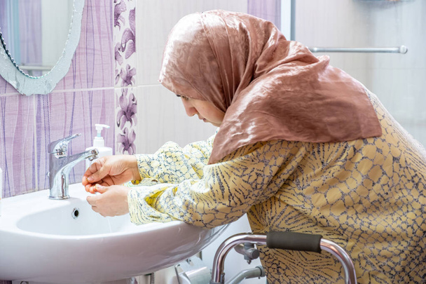 Muslimische Frau mit Behinderung wäscht sich die Hände - Foto, Bild