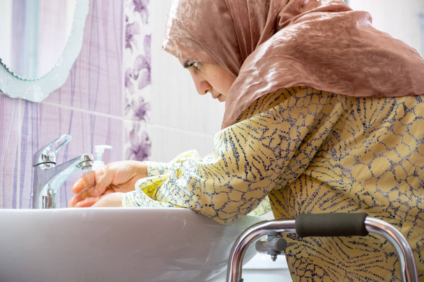 Muslimische Frau mit Behinderung wäscht sich die Hände - Foto, Bild