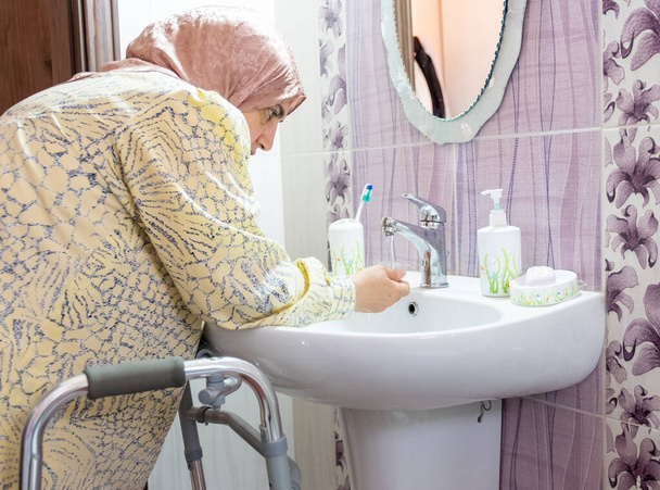 Moslim vrouw met een handicap wast haar handen - Foto, afbeelding