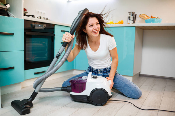 Jeune femme au foyer joue avec un aspirateur. Nettoyage d'appartement amusant - Photo, image