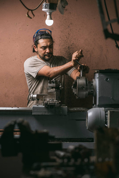 Чоловік працює в механічній майстерні зі своїми інструментами
 - Фото, зображення