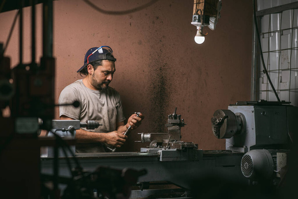 Man aan het werk in een werkplaats met zijn gereedschap - Foto, afbeelding