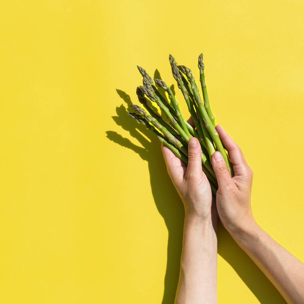 Fresh ripe asparagus with sunny, vivid, hard light and shadows. Creative pop art design concept. Trendy copy space illuminating yellow background - 写真・画像