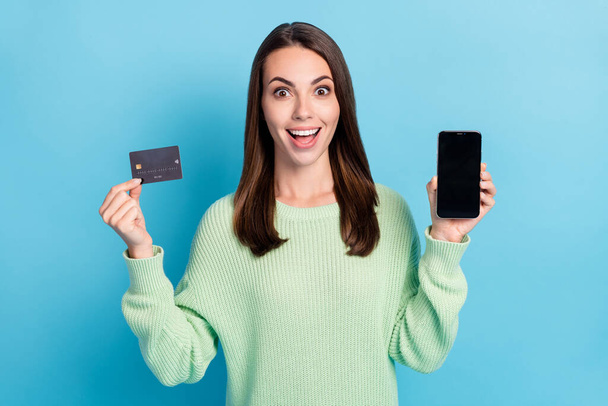 Photo portrait of girl demonstrating plastic bank debit card screen smartphone with copyspace isolated on vibrant blue color background - Foto, immagini