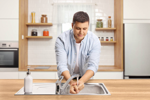 Man washing hands in a kitchen sink at home - Foto, afbeelding