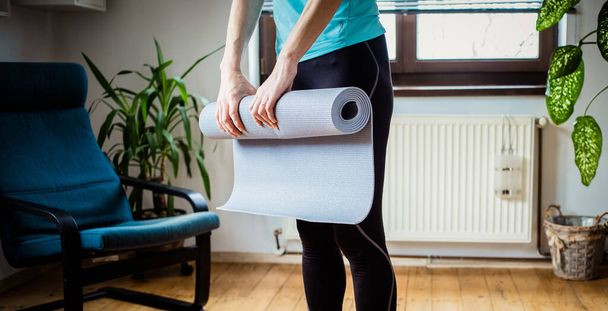 woman folding yoga mat at home - Φωτογραφία, εικόνα