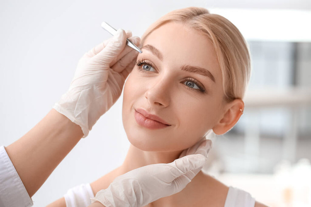 Jeune femme subissant une procédure de correction des sourcils dans un salon de beauté - Photo, image
