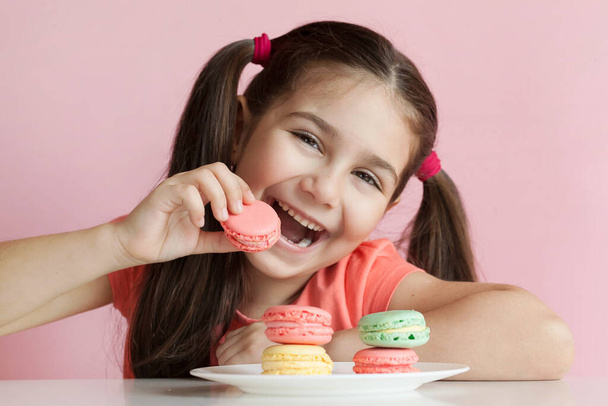 κορίτσι τρώει χρωματιστά αμυγδαλωτά  - Φωτογραφία, εικόνα