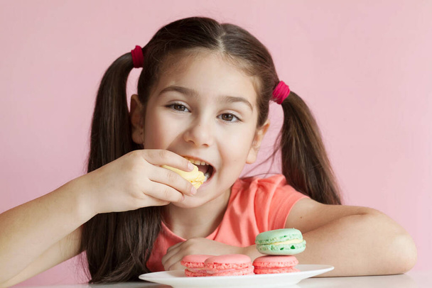 dziewczyna jedzenie kolorowe makaroniki  - Zdjęcie, obraz