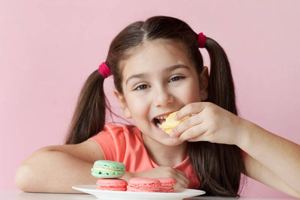 Kız renkli badem kurabiyesi yiyor.  - Fotoğraf, Görsel