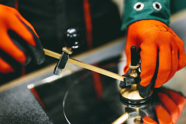 Працівник Глазьє ріже скло з компасом скляного різака в майстерні. промисловості
 - Фото, зображення