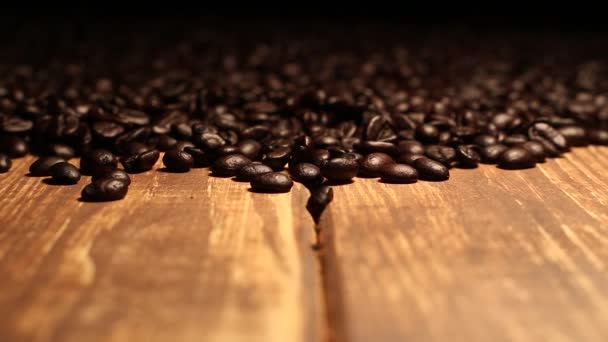 コーヒー豆で覆われた木製のテーブルの上に落ちるローストコーヒー豆 - 映像、動画