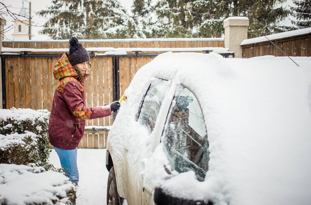 woman cleaning snow from car after blizzard - Photo, Image