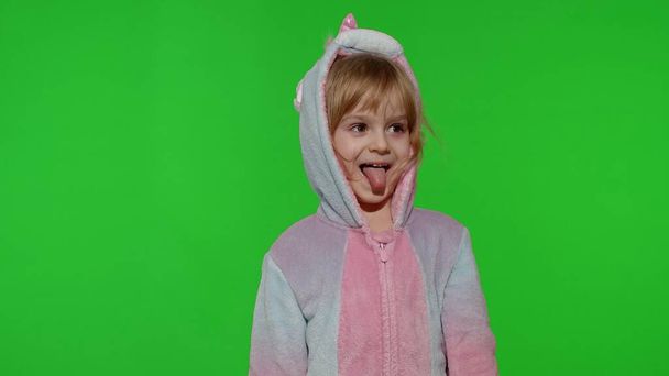 Menina criança em pijama unicórnio fazendo caras engraçadas bobas, brincando, mostrando a língua na tecla chroma - Foto, Imagem