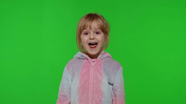 Bambino ragazza in pigiama unicorno fare stupide facce divertenti, scherzare in giro, mostrando la lingua sul tasto chroma - Foto, immagini