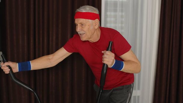 Terveet vanhukset vanhempi isoisä malli käyttää urheilua harjoitus orbitrek huoneessa kotona - Valokuva, kuva