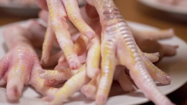 A mão feminina coloca patas de frango frescas em uma placa. Home Kitchen. Zoom. Close-up - Filmagem, Vídeo