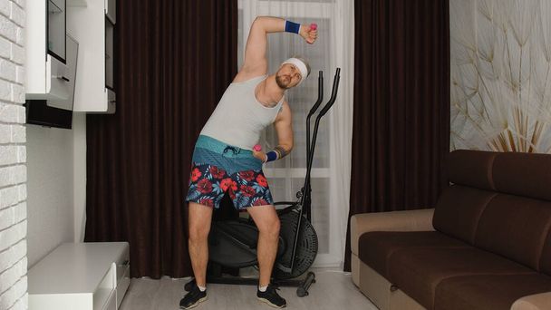 Grappige atleet sporter guy trainer het maken van oefeningen met halters, sport online vlog thuis - Foto, afbeelding