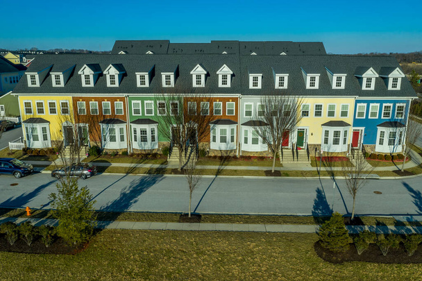 Τυπική αμερικανική πόλη σπίτι, πόλη σπίτι γειτονιά πολλαπλών-οικογενειακό έργο ανάπτυξης με πολύχρωμα ακίνητα σπίτια σε μια νέα κατασκευή Ανατολική Ακτή Maryland τοποθεσία από τον αέρα με γαλάζιο ουρανό - Φωτογραφία, εικόνα