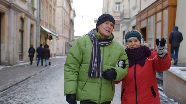 Idős pár nagymama és nagyapa színes télikabátban séta a téli városban - Fotó, kép