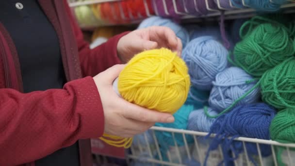 女の子は趣味の店で編み物や針仕事のための糸を選択します - 映像、動画
