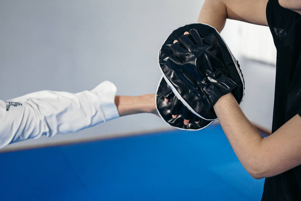 Entraînement personnel art martial du taekwondo. Entraîneur féminin tenant le tampon de coup de pied de taekwondo, l'entraîneur d'athlète donne des coups de pied. Femme frappant le bouclier de frappe, s'entraînant avec l'entraîneur. Chasseurs s'entraînent ensemble. - Photo, image