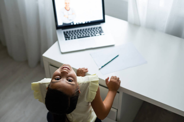 home, leisure, technology and internet concept - mała studentka z laptopem w domu, mała dziewczynka korzysta z czatu wideo - Zdjęcie, obraz