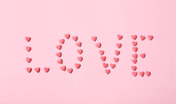 Word Love made with heart shaped sprinkles on pink background, flat lay - Фото, зображення