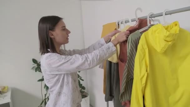 Pov nierozpoznawalny mężczyzna pomaga jego dziewczyna ubierać, wybierając ubrania, które trzyma na wieszaki - Materiał filmowy, wideo