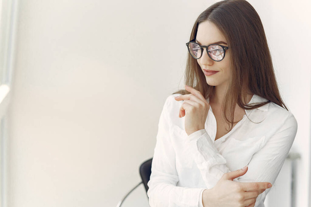Businesswoman in a white shirt sitting in the office - Foto, afbeelding