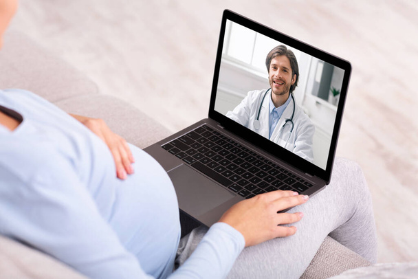 Consultation prénatale en ligne. Femme enceinte ayant un appel vidéo avec un médecin sur ordinateur portable de la maison - Photo, image