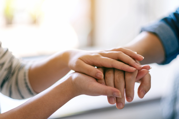 Ein Mann und eine Frau halten einander die Hand, um Trost und Anteilnahme zu spenden - Foto, Bild