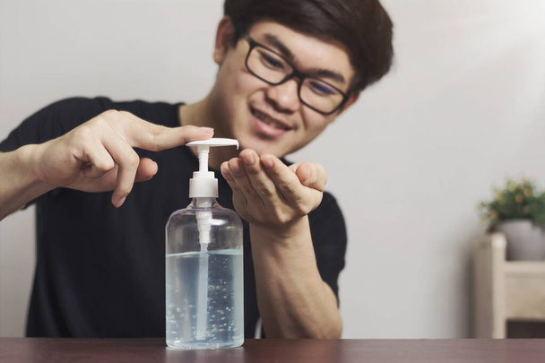 Limpiando las manos. Los hombres asiáticos sonríen, felices de lavarse las manos con alcohol para prevenir el virus pandémico de la corona en casa. El concepto de prevención de una epidemia grave - Foto, imagen