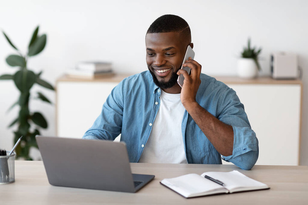 Zdalny biznes. czarny mężczyzna freelancer Worjing z telefon komórkowy i laptop w domu - Zdjęcie, obraz