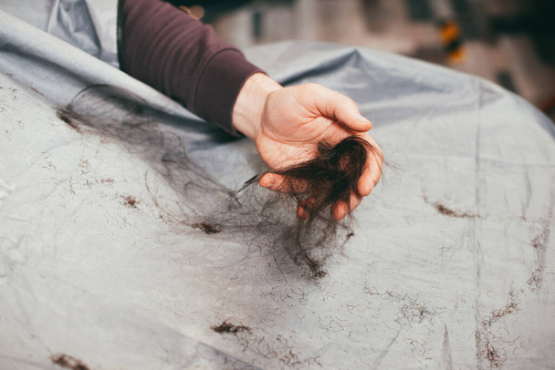 Mann hält beim Friseur seine geschnittenen Haare in den Händen - Foto, Bild
