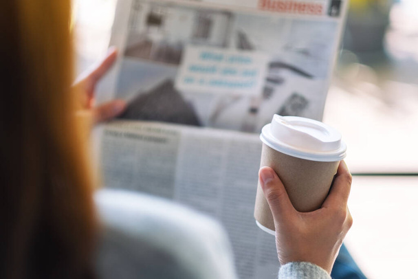 Closeup image of a woman reading newspaper and drinking coffee in the morning - 写真・画像