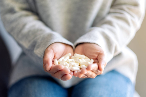 Szoros kép egy nőről, aki fehér gyógyszerkapszulát tart a kezében - Fotó, kép