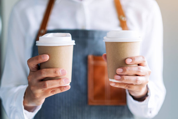 A waitress holding and serving two paper cups of hot coffee in cafe - Foto, afbeelding