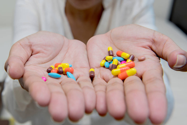 Στην επιλεκτική εστίαση των τρελών γυναικών τρώει πολλά χάπια στο χέρι. Δραματική στιγμή. - Φωτογραφία, εικόνα