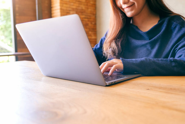 Szoros kép egy gyönyörű nő dolgozik és gépel laptop számítógép fa asztalon - Fotó, kép