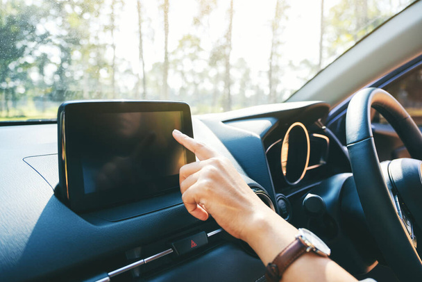 車を運転している間にナビゲーション画面で指を使用し、指差す女性の画像を閉じます - 写真・画像