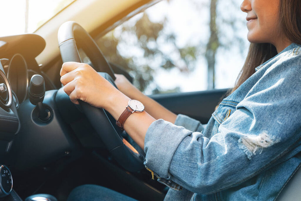 Imagen de cerca de una mujer sosteniendo el volante mientras conduce un coche - Foto, imagen
