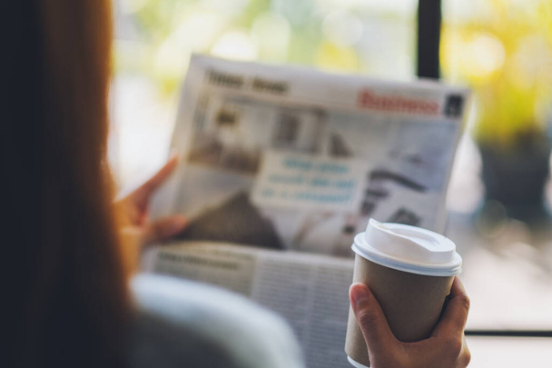 Closeup image of a woman reading newspaper and drinking coffee in the morning - Φωτογραφία, εικόνα