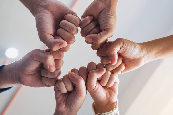 Low angle view image of people putting their fisted hands in circle together - Photo, image